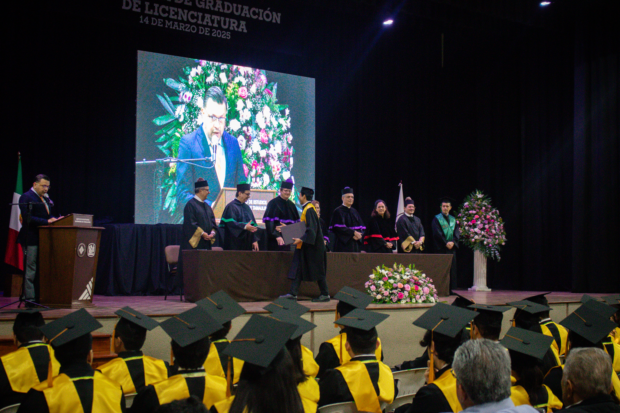 Alumnos recibiendo sus documentos en ceremonia de graduación.