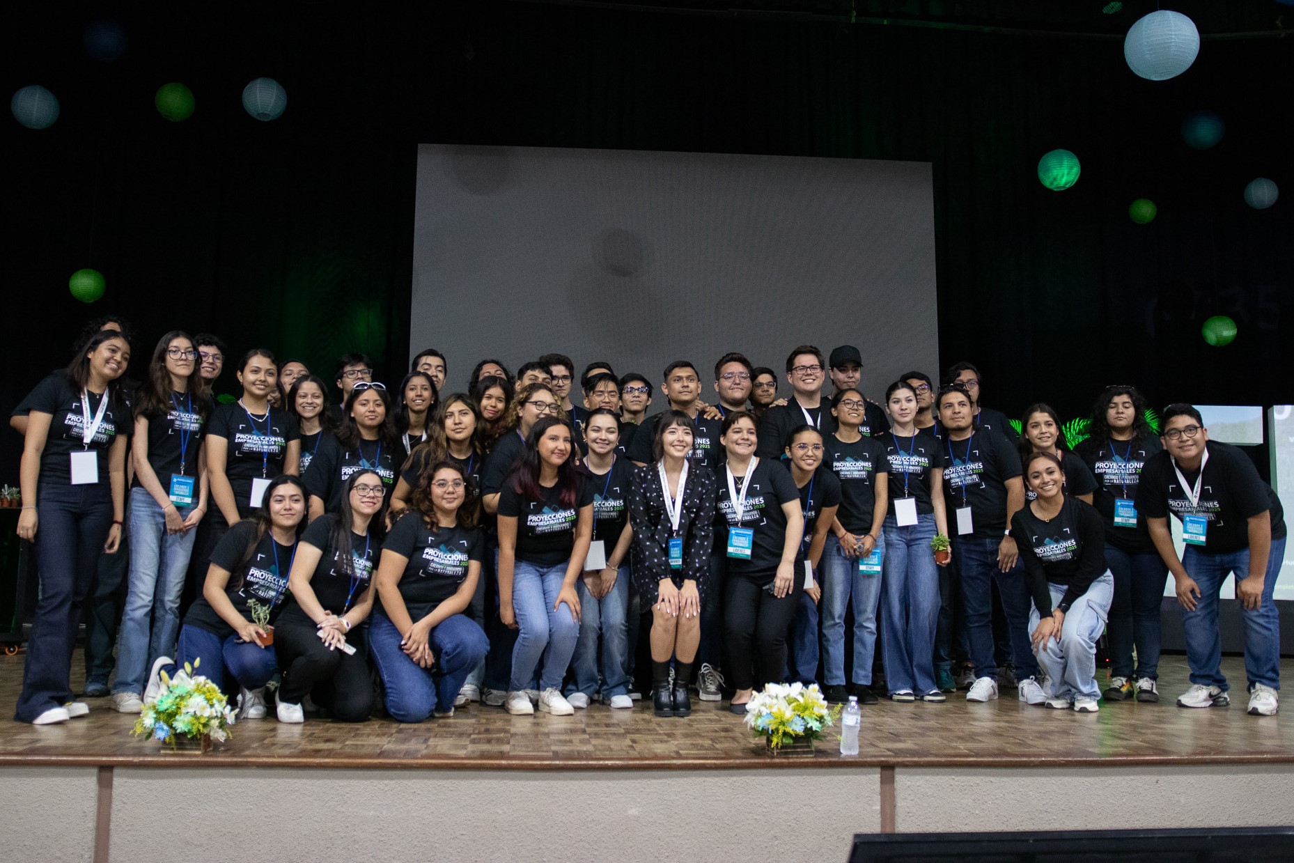Foto de grupo de organizadores de Proyecciones Empresariales, en el escenario del gimnasio.