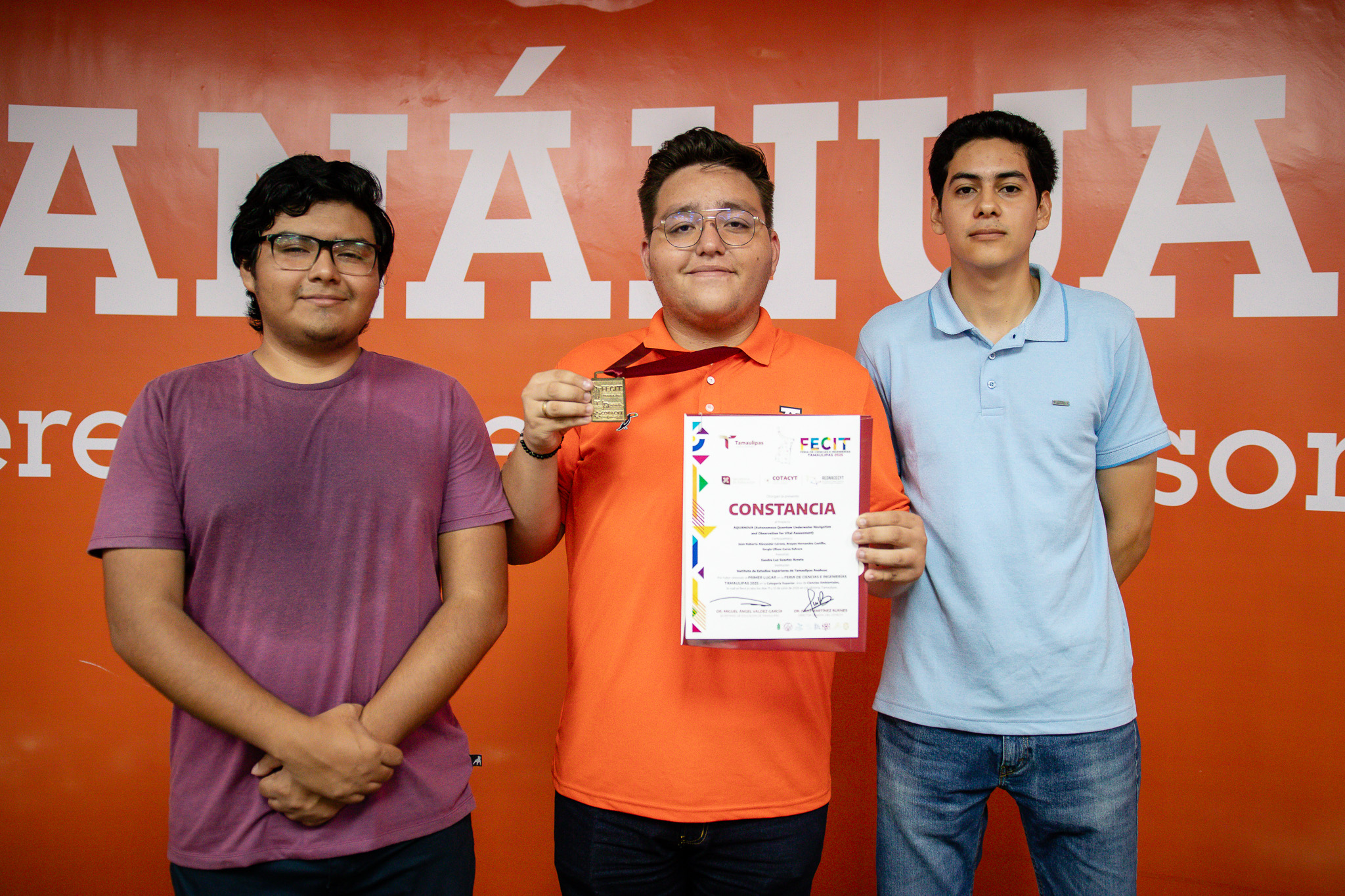 Tres alumnos integrantes de AquaNova, mostrando su diploma de triunfo.