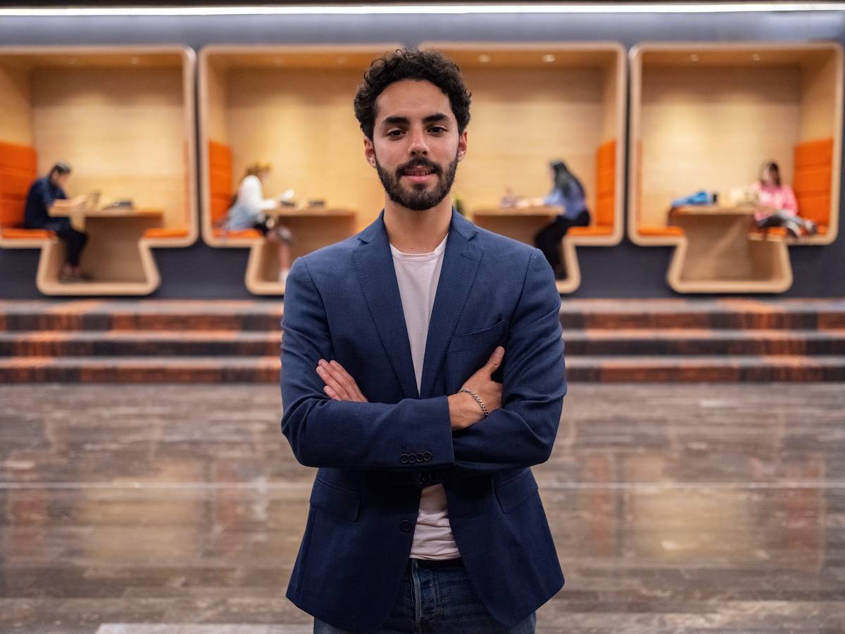 Estudiante de administración pública y gobierno de pie con actitud segura en un entorno académico moderno, representando liderazgo, profesionalismo y colaboración.