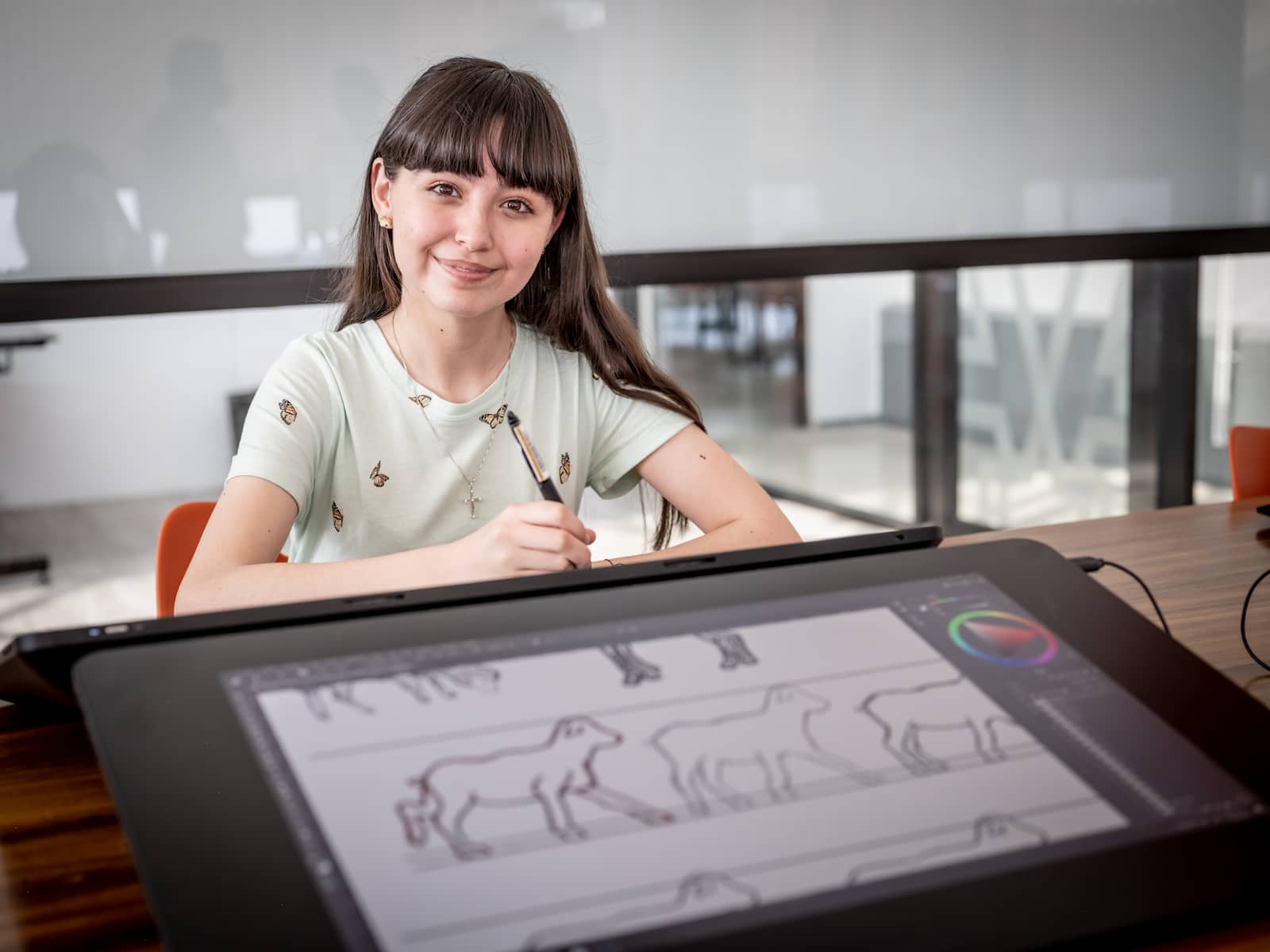 Estudiante de diseño digital usando una tableta gráfica para dibujar un animal en su proyecto, mostrando concentración y creatividad.