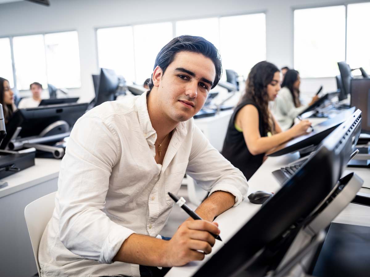 Estudiante de Inteligencia Estratégica trabajando con lápiz digital en una pantalla interactiva, en un aula tecnológica junto a sus compañeros, reflejando análisis visual, pensamiento estratégico y uso avanzado de herramientas digitales.